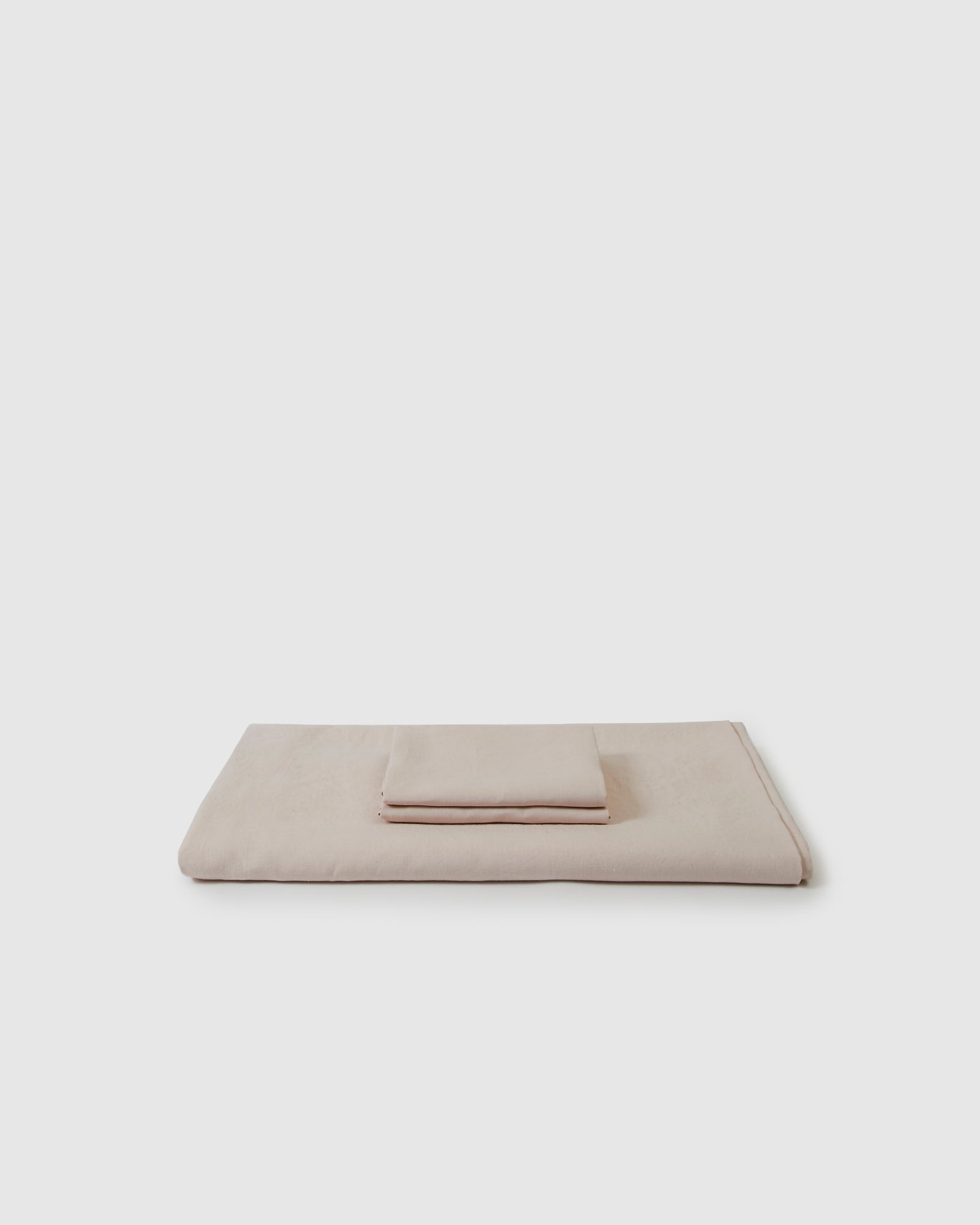 Side angle shot of linen duvet cover and pair of pillowcases in light blush pink
