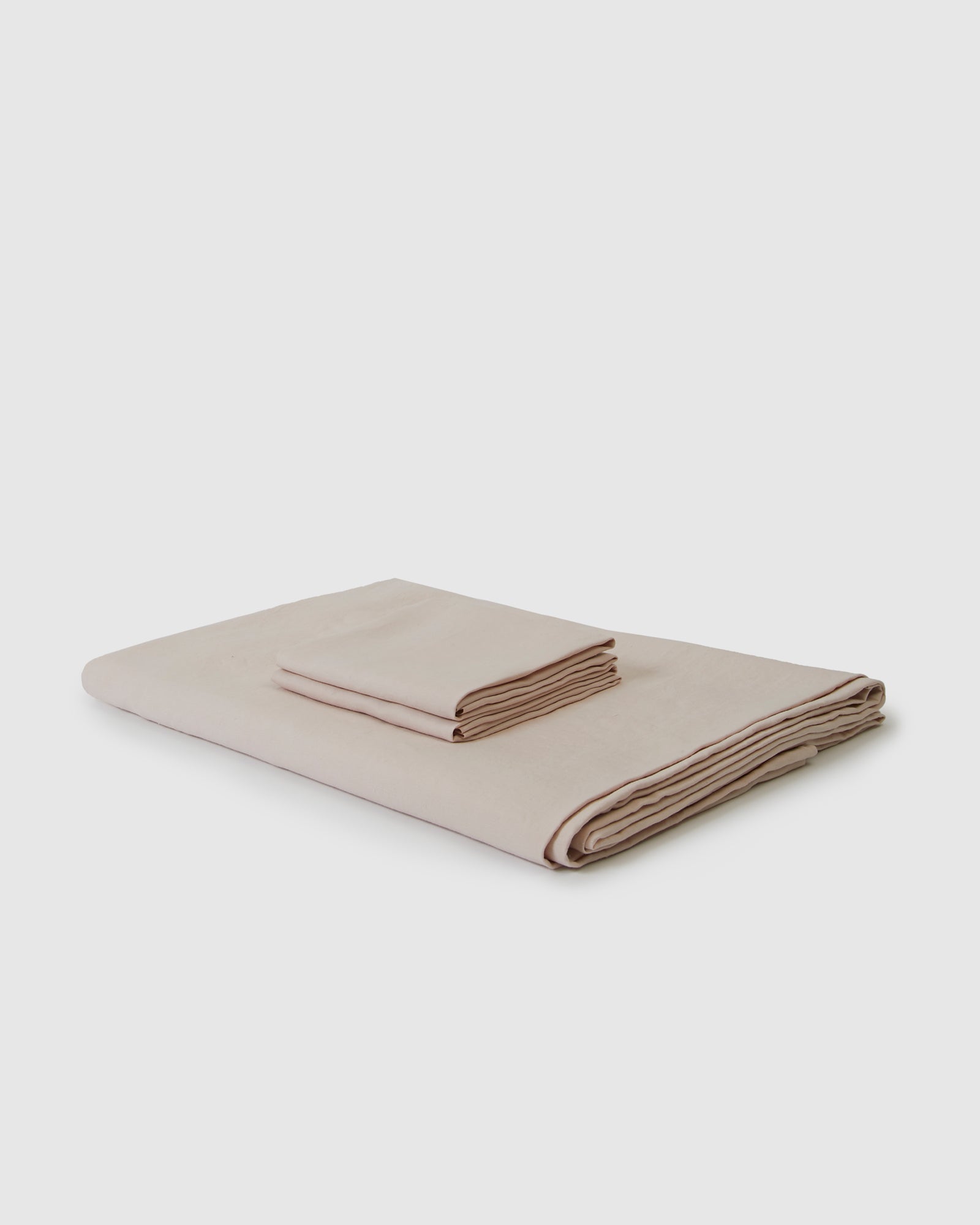 Side angle shot of linen duvet cover and pair of pillowcases in light blush pink