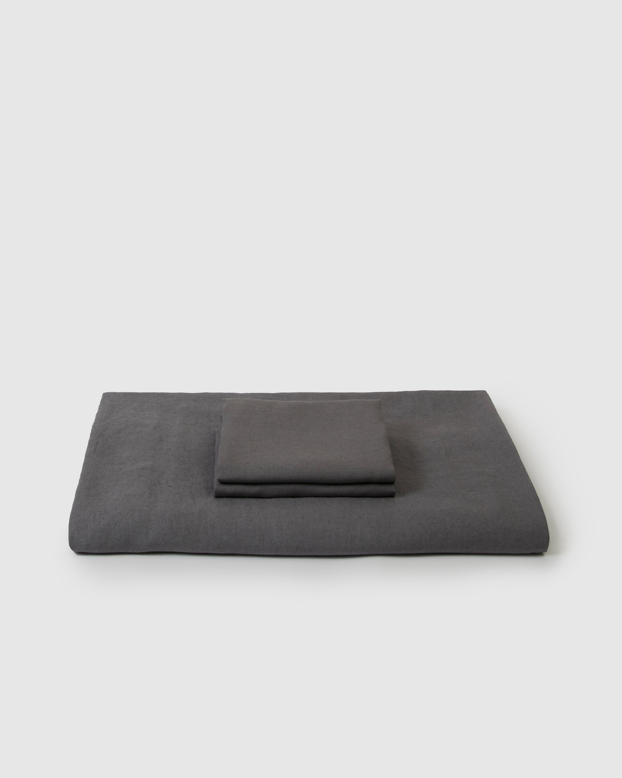 Side angle shot of linen duvet cover and pair of pillowcases in storm dark gray