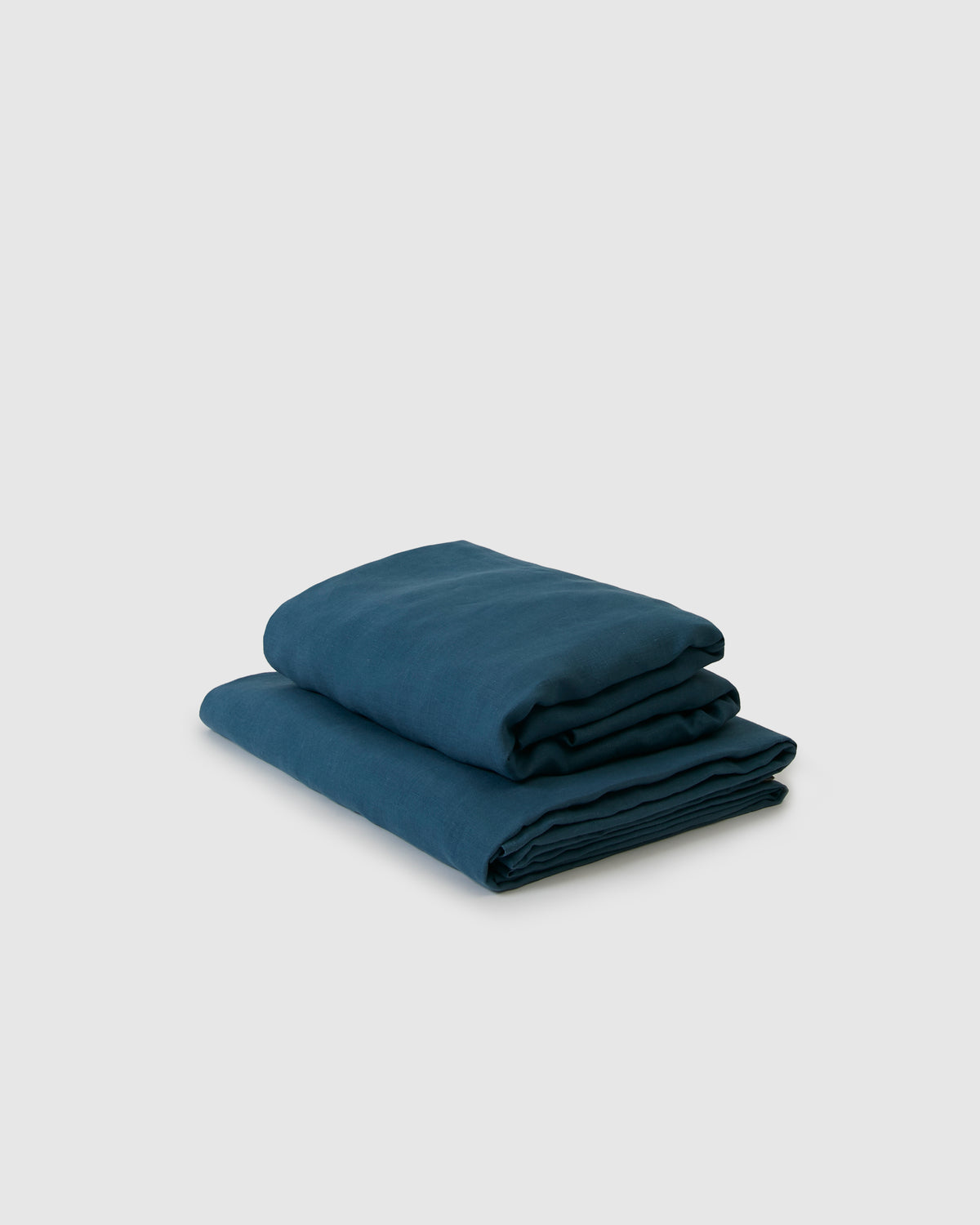 Side angle shot of dark adriatic blue flat and fitted sheet set