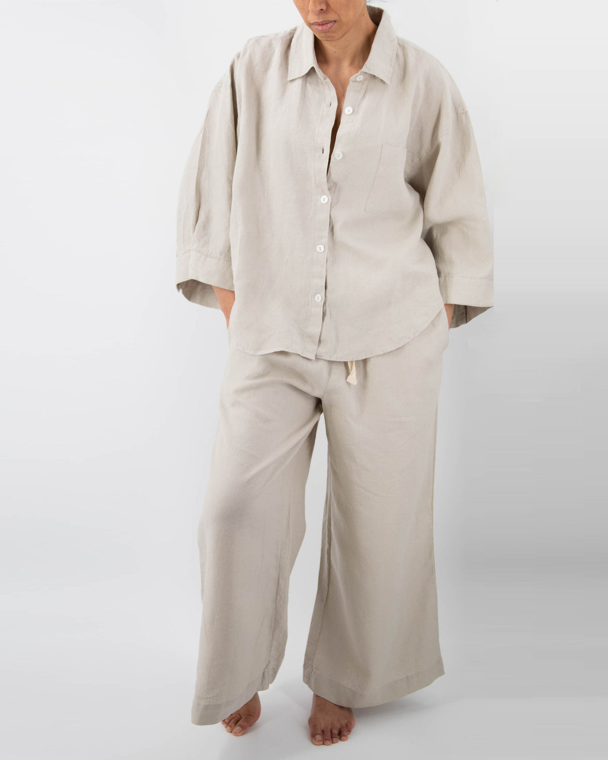 Model in dove gray linen pajamas (long sleeved shirt and long pants)