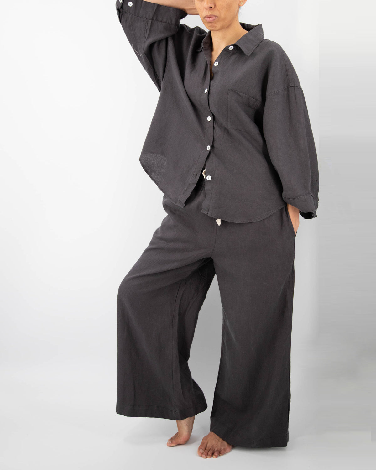 Model in charcoal black linen pajamas (long sleeved shirt and long pants)