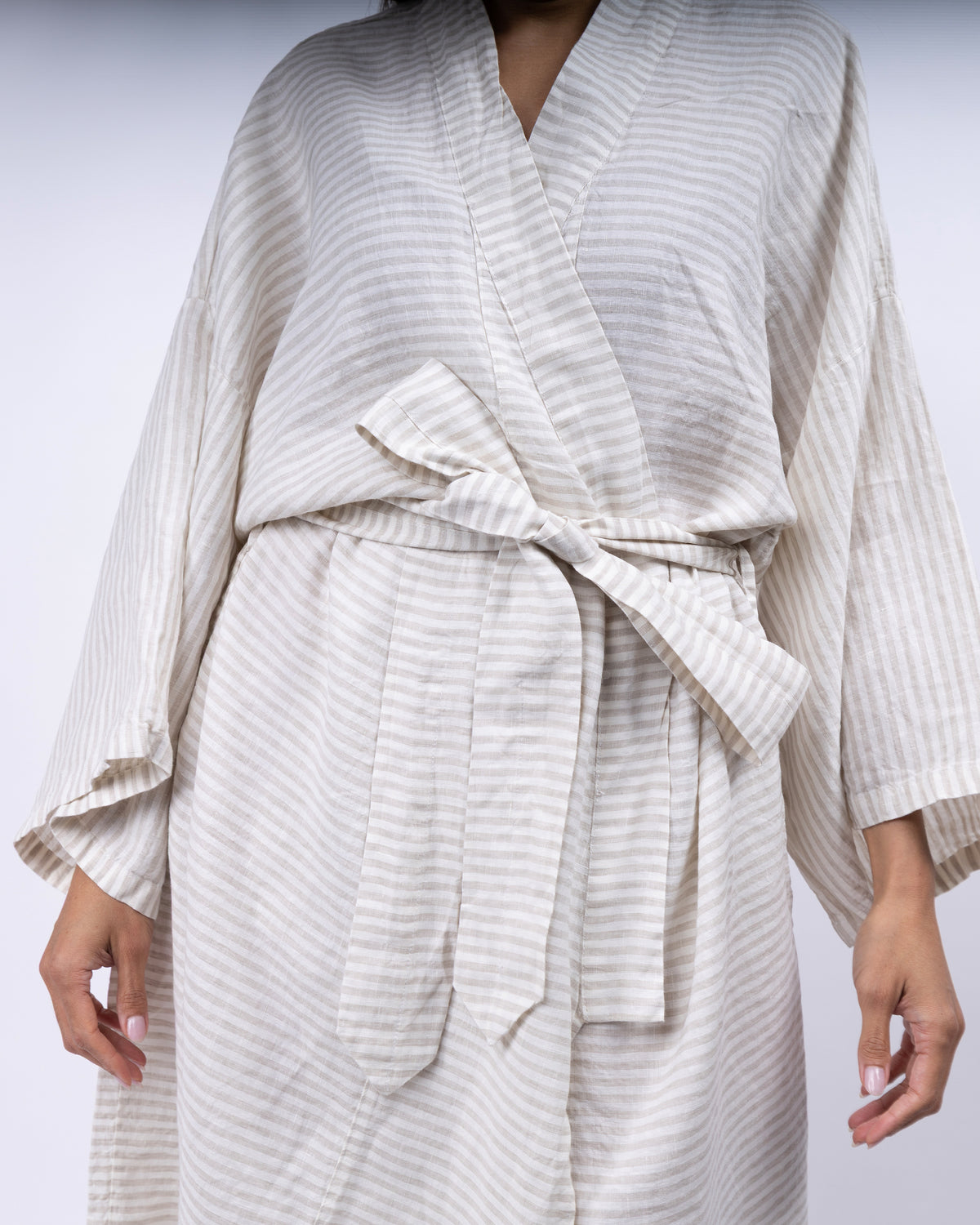 Person wearing a white striped robe on a light gray background