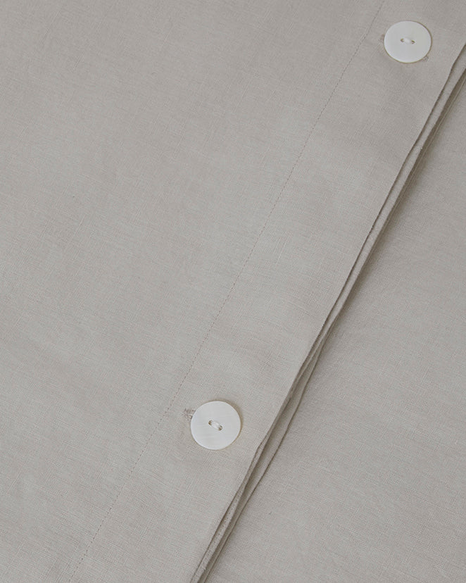 Close-up shot of light dove gray linen duvet cover with mother of pearl button