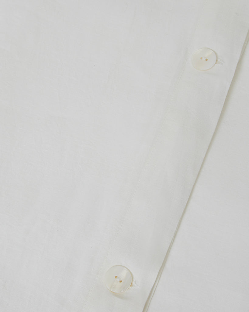 Close-up shot of creamy white milk linen duvet cover with mother of pearl button