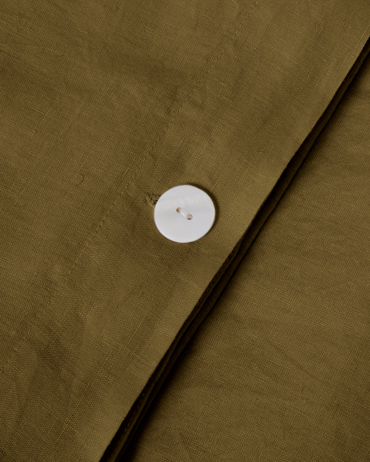 Close-up shot of moss green linen duvet cover with mother of pearl button