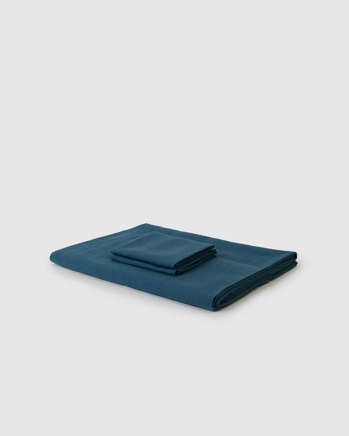 Side angle shot of linen duvet cover and pair of pillowcases in dark blue adriatic
