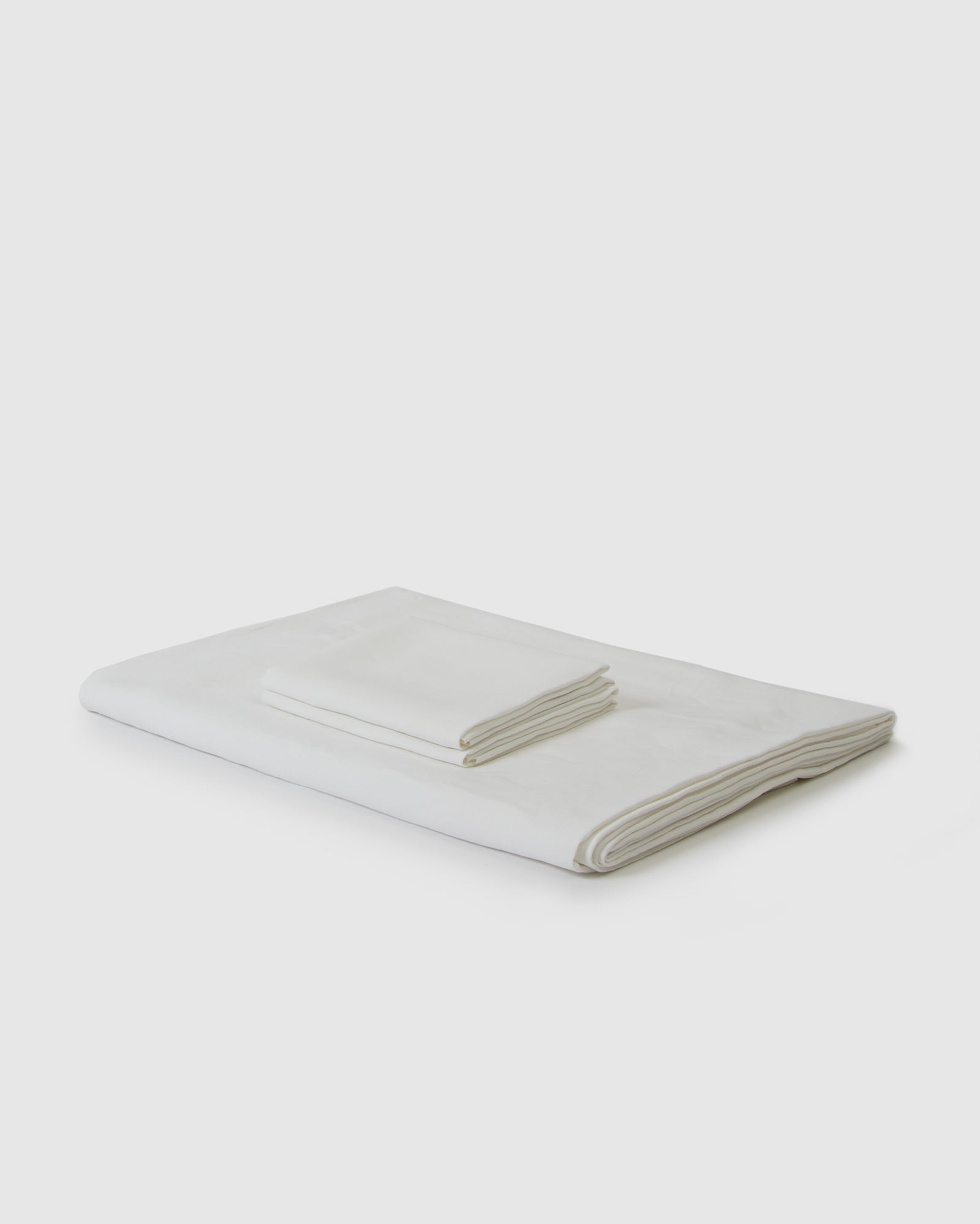 Side angle shot of linen duvet cover and pair of pillowcases in creamy white milk