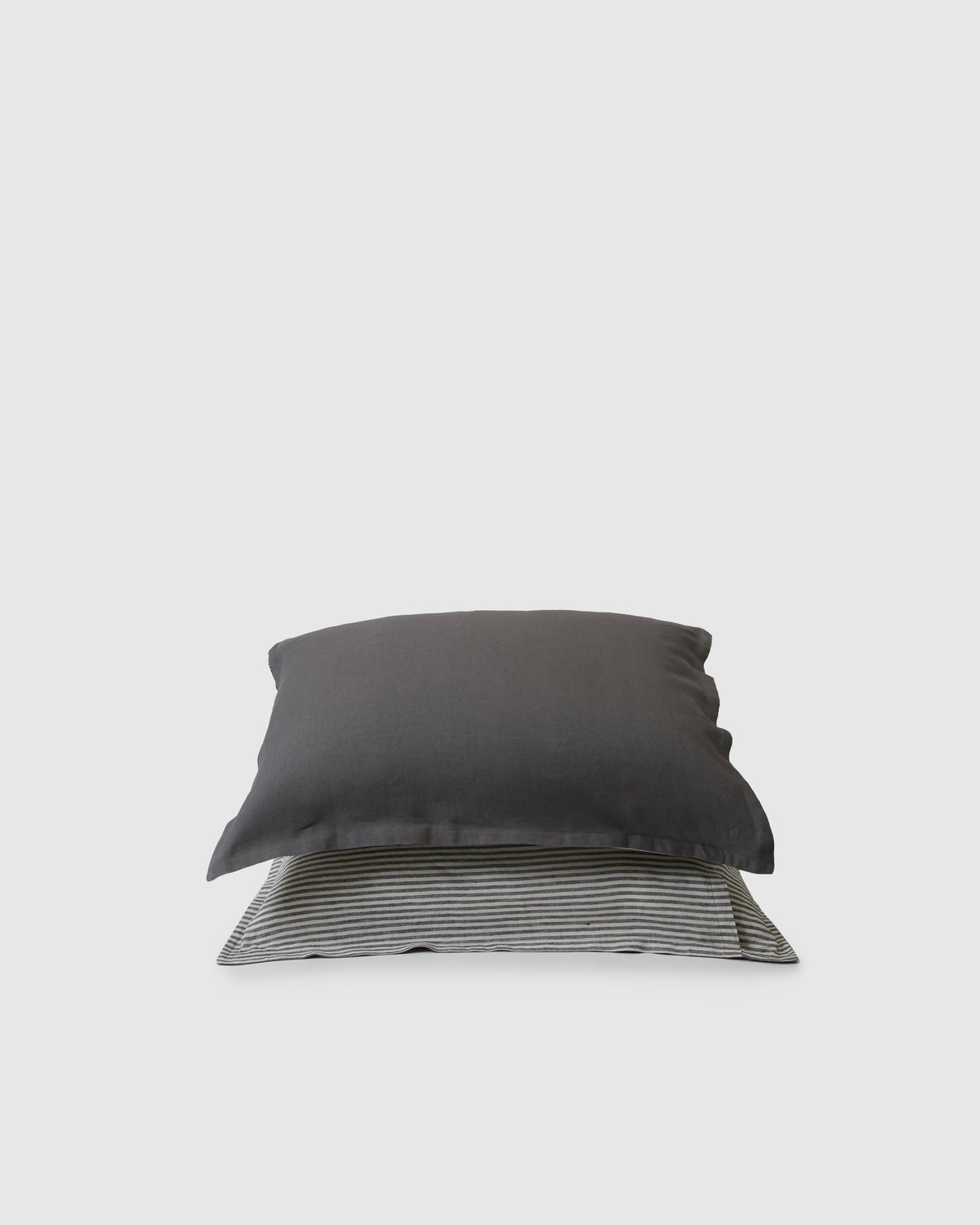Pair of filled pillowcases in storm dark gray on one side and storm stripe on the other