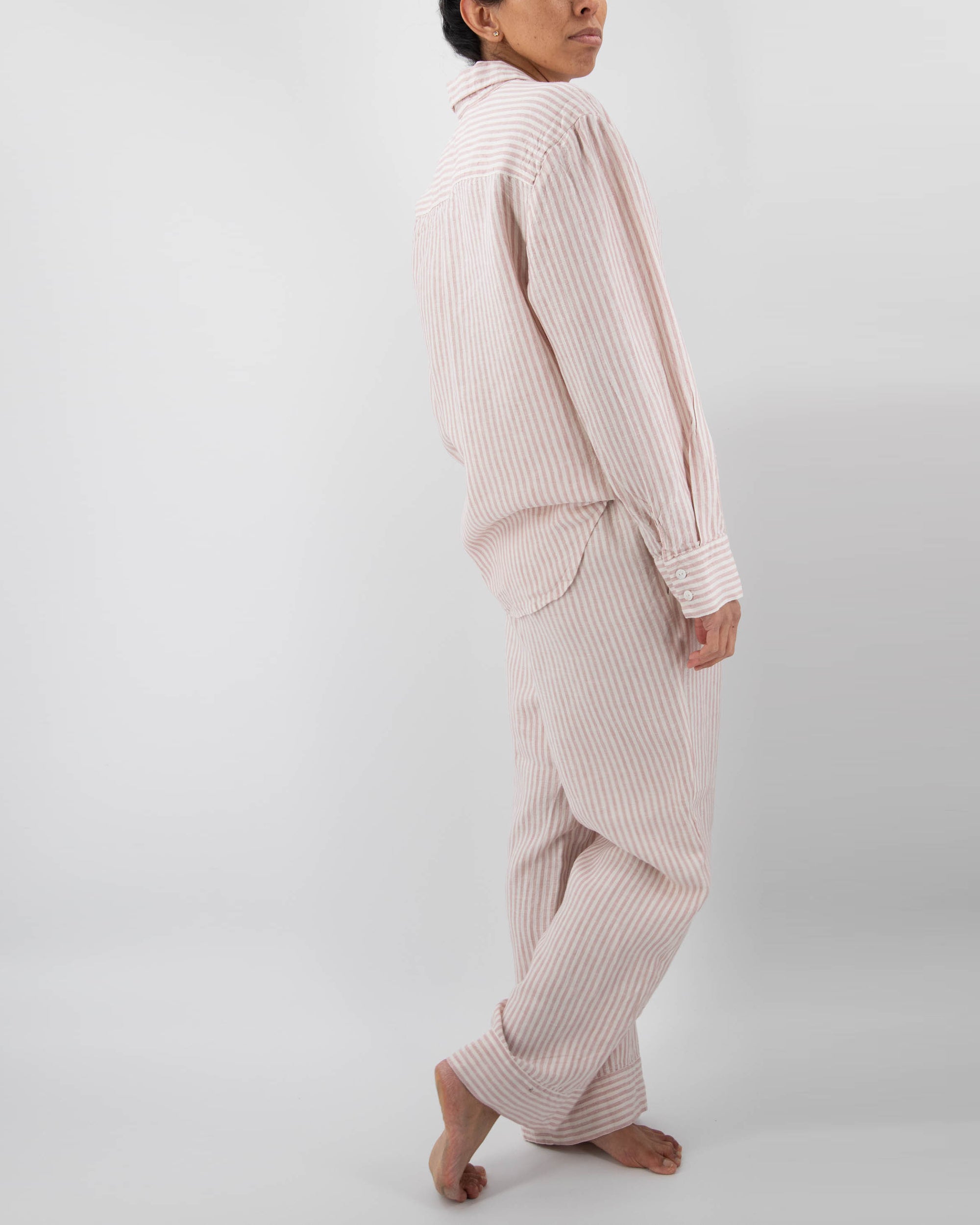 Model in pink linen striped pajamas (long sleeved shirt and long pants) 