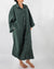 Side profile of model with full-length linen dress with buttons and front pocket in pine green 