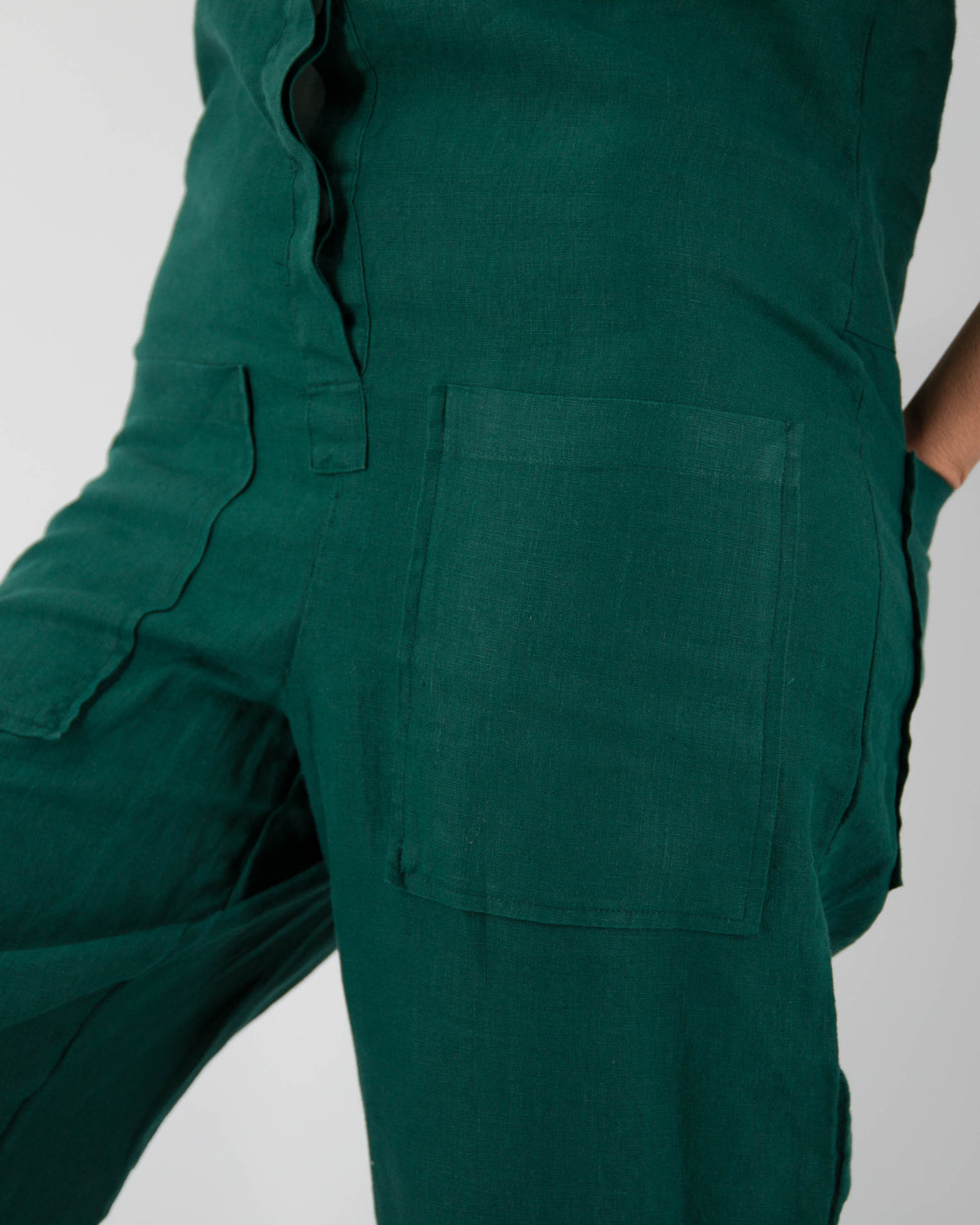 Close-up of front pockets of botanical green linen jumpsuit