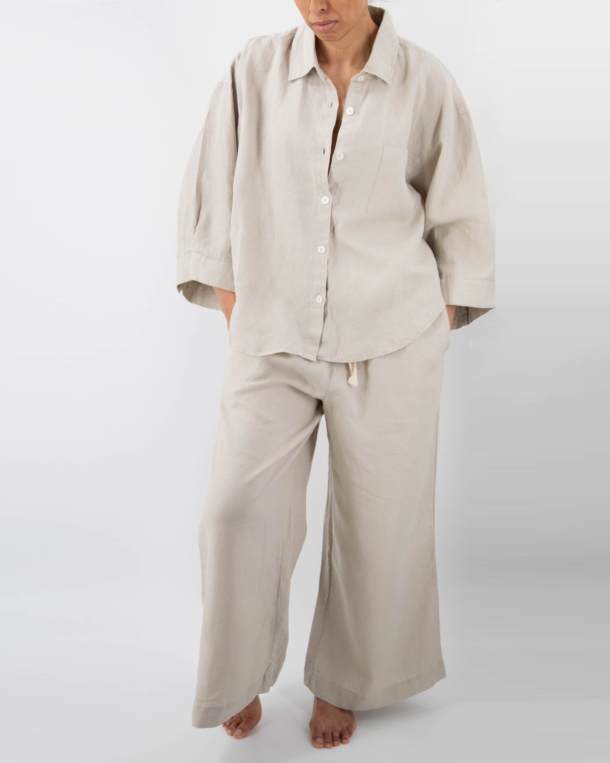 Model in dove gray linen pajamas (long sleeved shirt and long pants) 