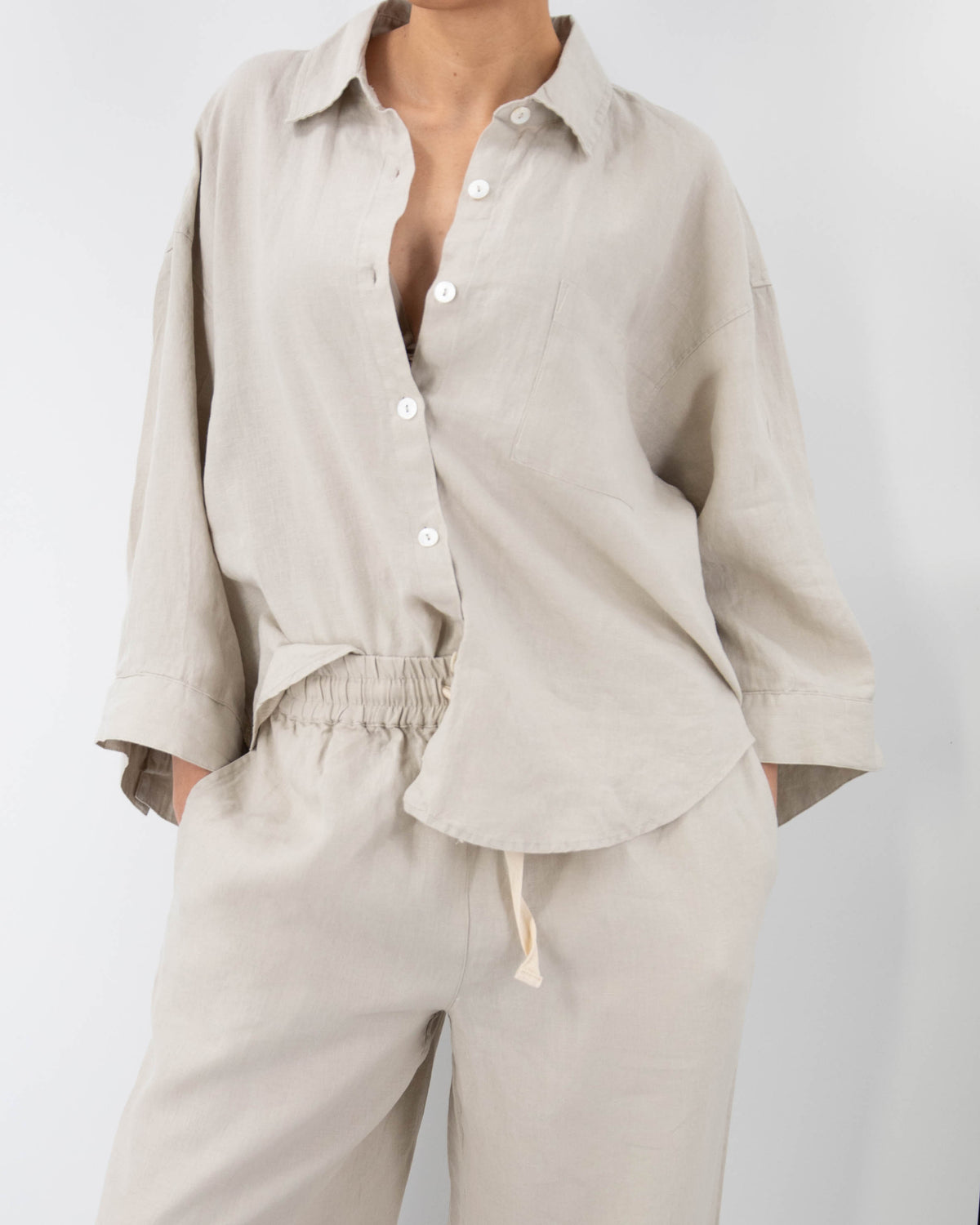 Close-up of model in dove gray linen pajamas (long sleeved shirt and long pants) 