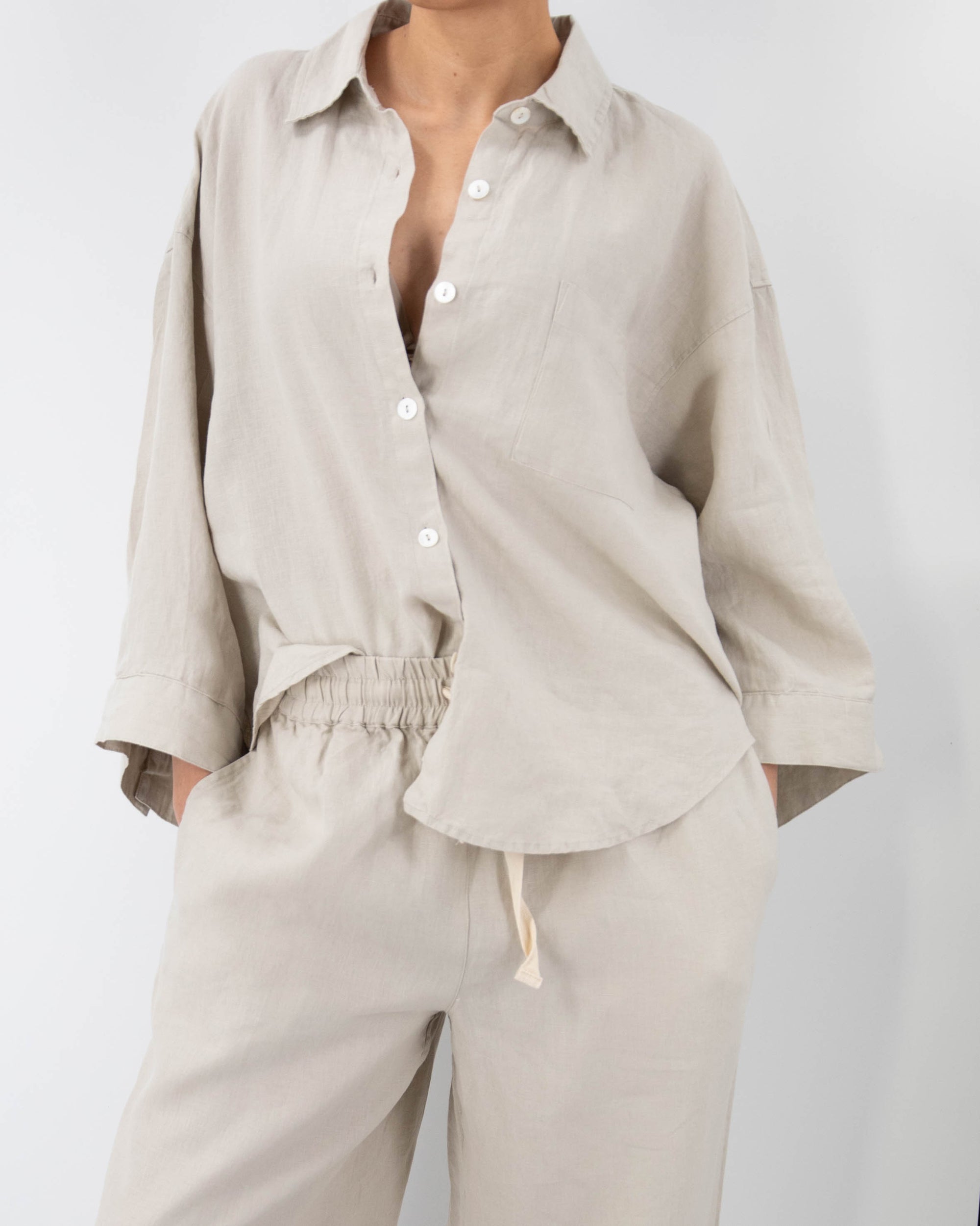 Model in dove gray linen pajamas (long sleeved shirt and long pants) 